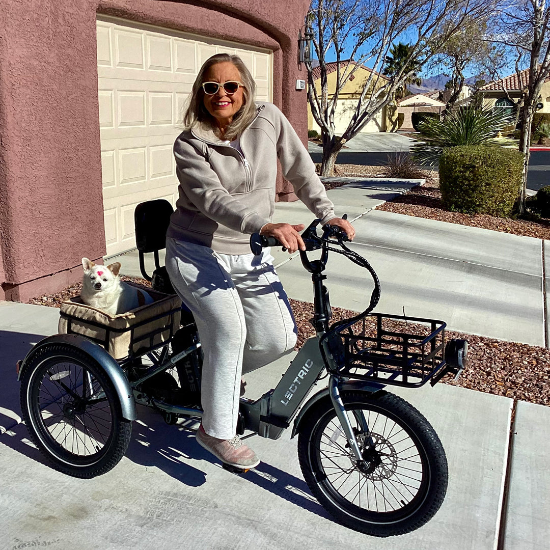 woman riding trike with dog in basket